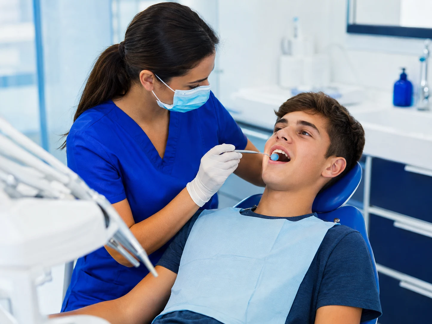 Adolescente recebendo atendimento de uma dentista em consultório com tons de azul e branco